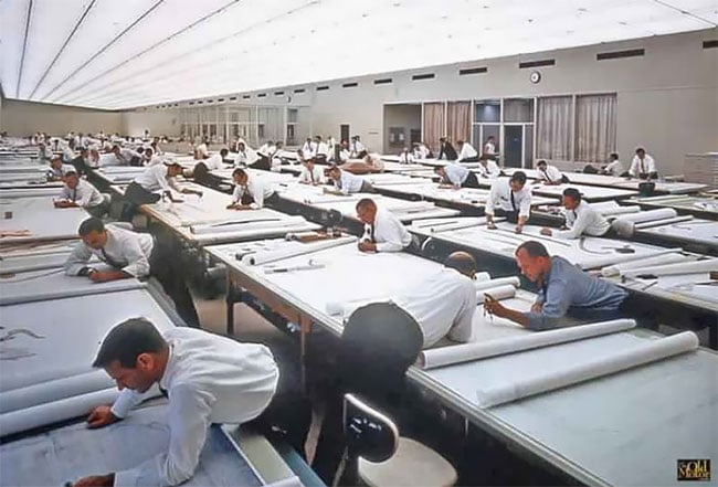 Sala de delineación de los años ochenta: decenas de tableros en
                  filas y un delineante en cada uno, dibujando a mano.