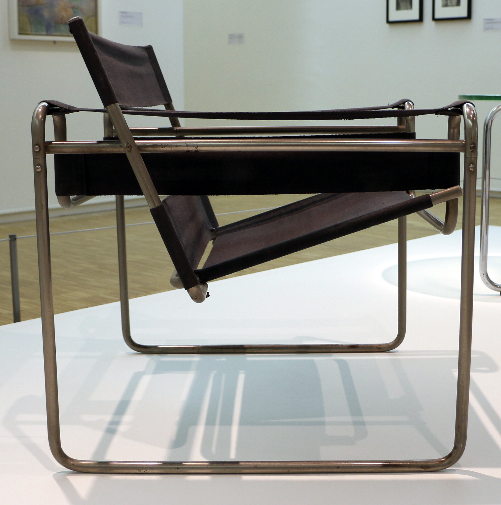 La butaca B3 «Wassily» de Marcel Breuer: una estructura de tubo
                de acero cromado, doblado, con cinchas de tela tensadas como
                asiento, respaldo y brazos.